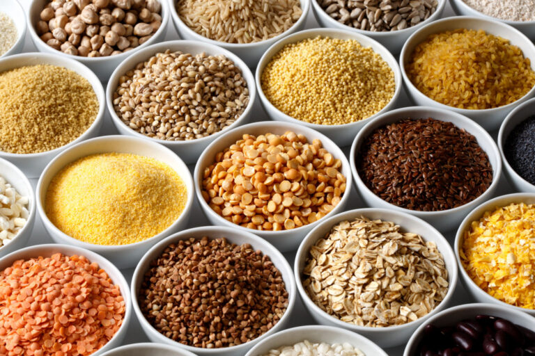 Background of many grains and pulses in white ceramic dishes.