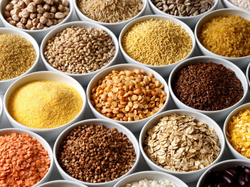Background of many grains and pulses in white ceramic dishes.